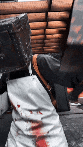 a person with blood on their pants is standing in front of a wooden wall