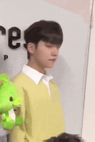 a young man in a yellow shirt is holding a stuffed animal and a sign that says new year !