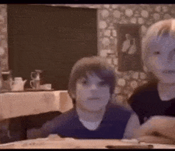 two young boys are sitting at a table in a kitchen .