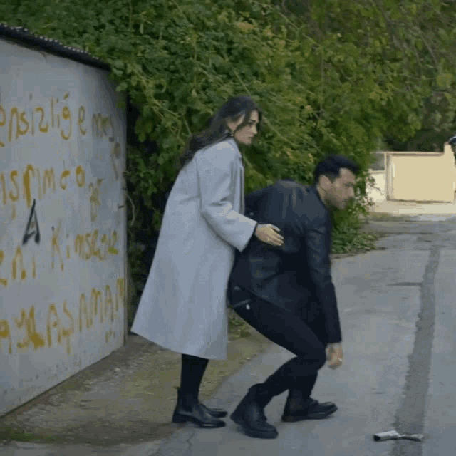 a man and a woman are standing in front of a wall that says a kimse
