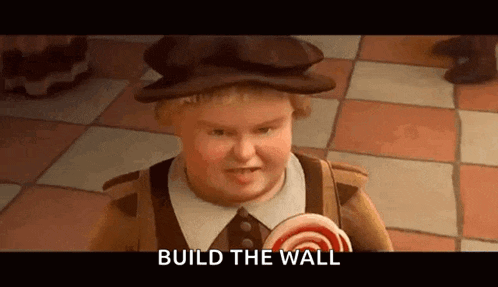 a cartoon character from shrek is holding a lollipop and says `` build the wall '' .