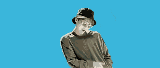 a man wearing a hat and sunglasses is standing in front of a blue sky