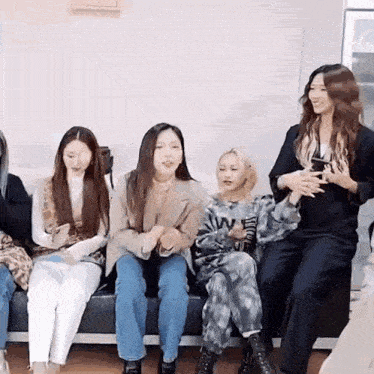 a group of women are sitting on a couch and talking to each other .