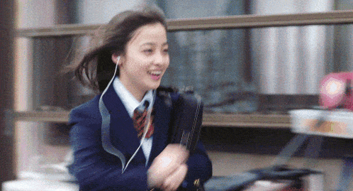 a girl in a school uniform is wearing ear buds