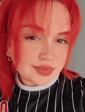 a woman with red hair is wearing a black and white striped shirt with the letter o on it