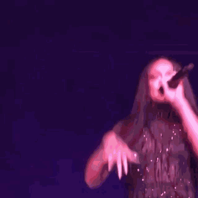 a woman is holding a microphone on a stage in a dark room .