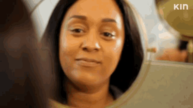 a woman is looking at her face in a mirror and smiling .