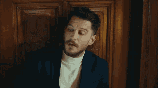 a man in a suit and white turtleneck looks up at the sky