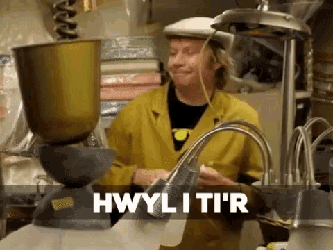 a woman in a yellow jacket is standing in front of a mixer and says hwylitir