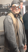 a man wearing sunglasses and a hat is standing in a room with other people .