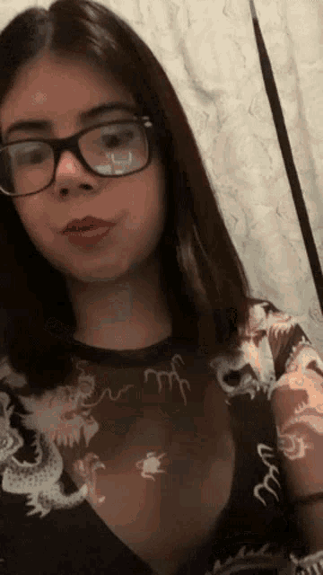 a woman wearing glasses and a black shirt with a dragon on it