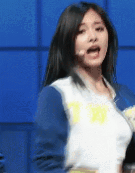 a woman wearing a blue jacket and a white t-shirt with the letter t on it