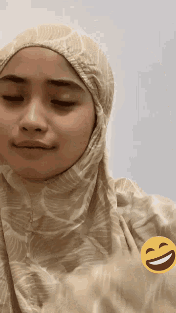 a woman wearing a hijab with a smiley face on the bottom right