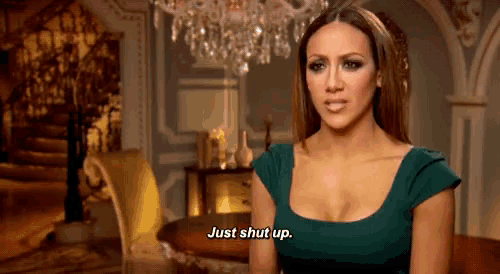 a woman in a green dress is sitting in front of a chandelier and saying just shut up .