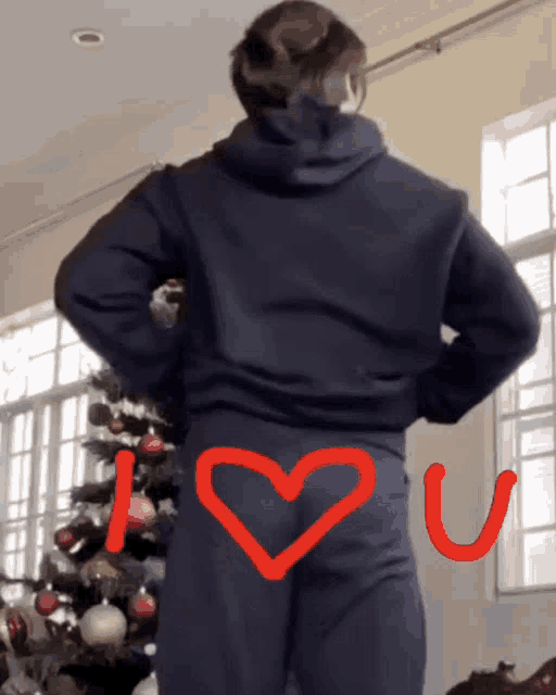 a person standing in front of a christmas tree with the words i love you written on their butt