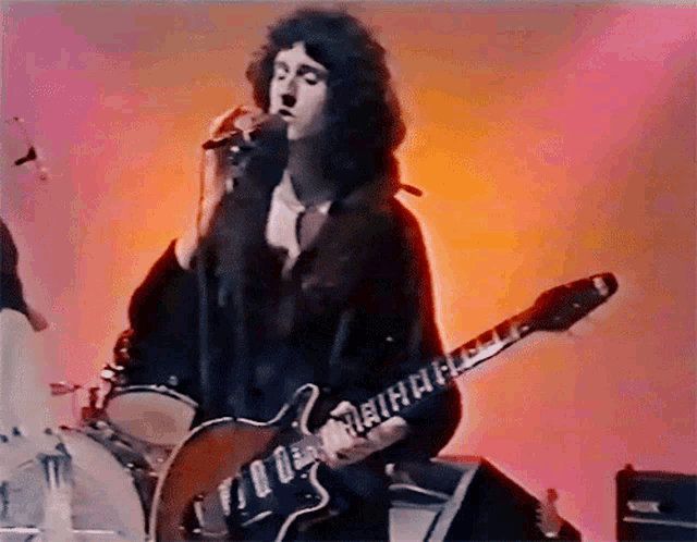 a man singing into a microphone and playing a guitar