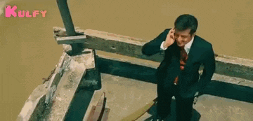 a man is laughing while talking on a cell phone in a chair .