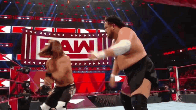 two men are wrestling in a ring with a sign that says raw on it