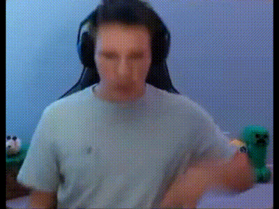 a man wearing headphones and a white t-shirt is sitting in front of a computer screen .