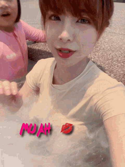 a woman in a bathtub with the word muah written on her chest