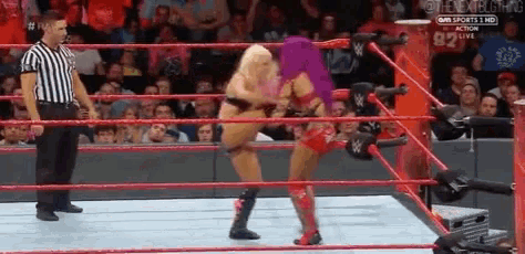 two women are wrestling in a wrestling ring while a referee looks on .