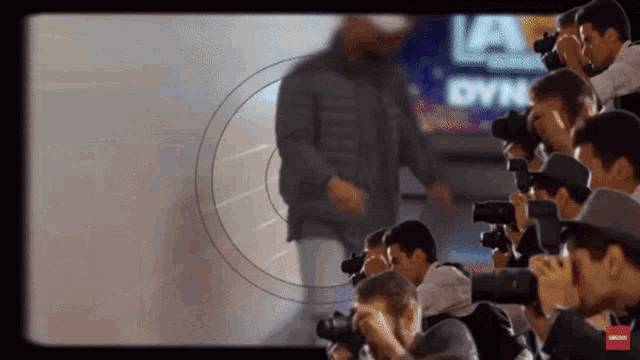 a group of people taking pictures of a man in front of a sign that says la dyne