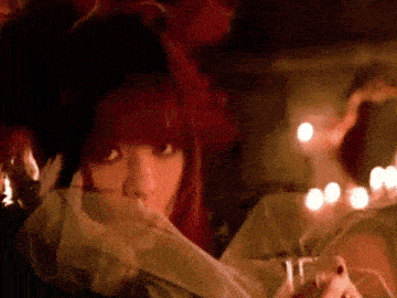 a woman with red hair is covering her face with a veil
