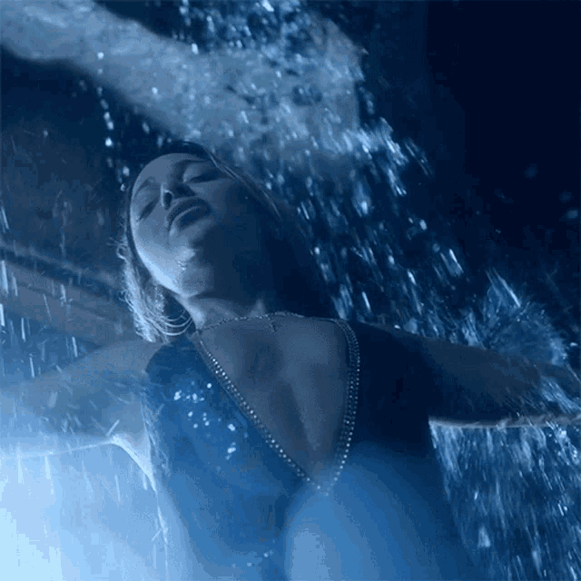 a woman in a blue dress is standing in the rain