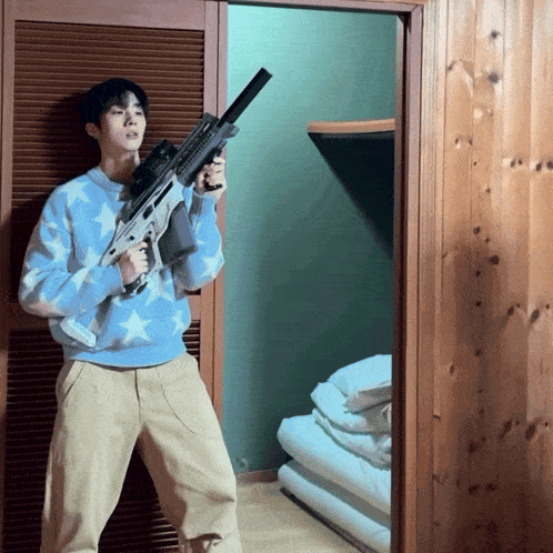 a man in a blue sweater is holding a rifle