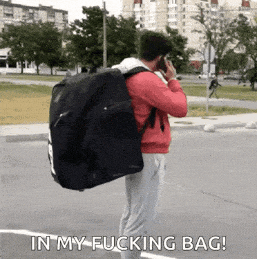 a man is carrying a large bag on his back and talking on a cell phone