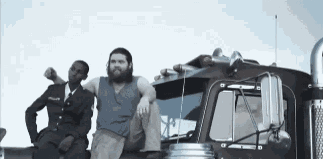 a man with a beard sits on the side of a truck