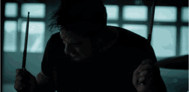 a man playing drums in a dark room