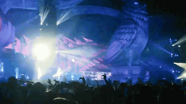 a crowd of people at a concert with a giant dragon in the background