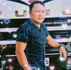 a man in a blue shirt is standing in front of a large truck .