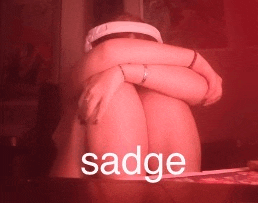 a woman is hugging her knees and the word sadge is visible