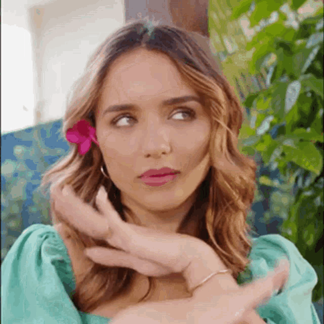 a woman with a pink flower in her hair is wearing a green top