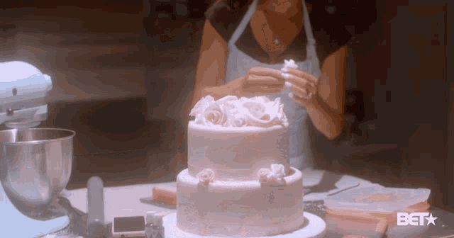 a woman decorates a cake with bet written on the bottom right
