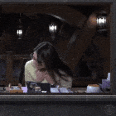 a woman in a yellow sweater and glasses is sitting at a desk