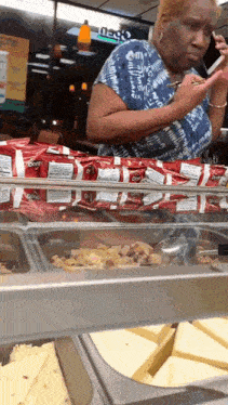 a woman is looking at her phone while standing in front of a display case of food
