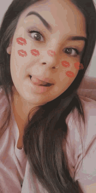 a woman is sticking her tongue out and has red kisses on her face