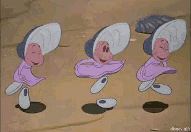 three cartoon characters from alice in wonderland are dancing on a sandy surface .
