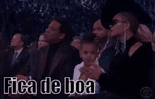 a group of people sitting in a stadium with the words fica de boa written on the screen .