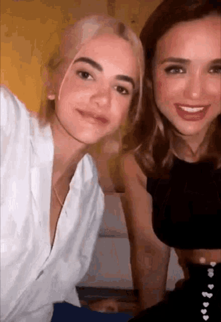 two women are posing for a picture and one is wearing a white shirt