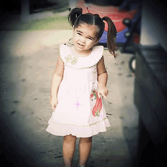 a little girl wearing a pink dress with a unicorn on it