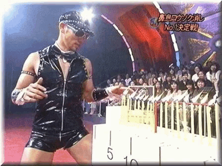 a man in a black outfit is standing in front of a crowd with a sign that says no. 1 on it