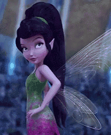 a fairy with purple hair and wings is wearing a green and pink dress and standing with her hands on her hips .