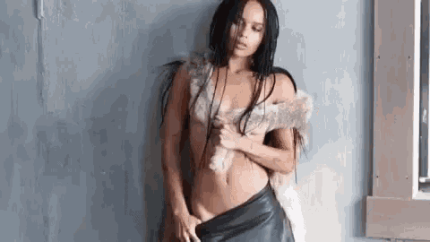 a naked woman is standing in front of a window holding a fur coat .