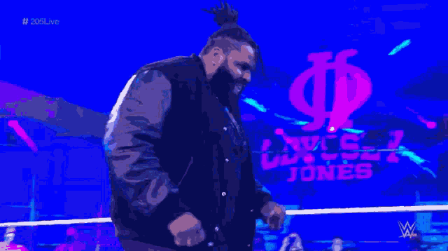 a man in a black jacket is standing in front of a screen that says wwe