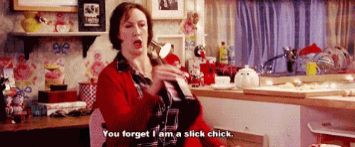 a woman is sitting in a kitchen holding a spoon and saying " you forget i am a slick chick .