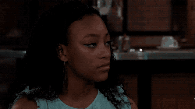 a girl with curly hair is wearing a blue shirt